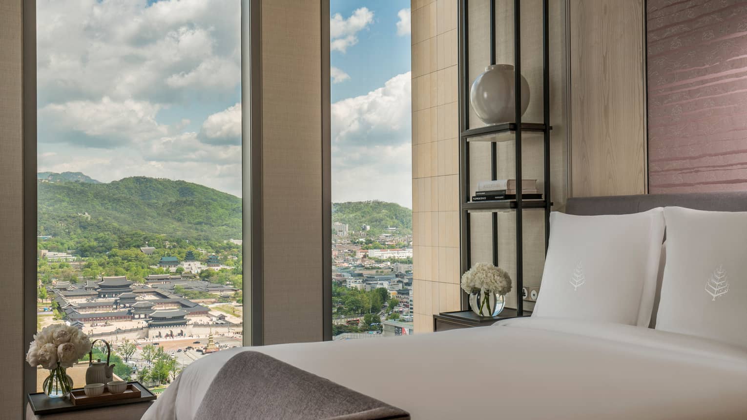 Palace-View Executive Suite bed, chaise at foot, shelf with vases, books beside window overlooking Gyeongbokgung Palace