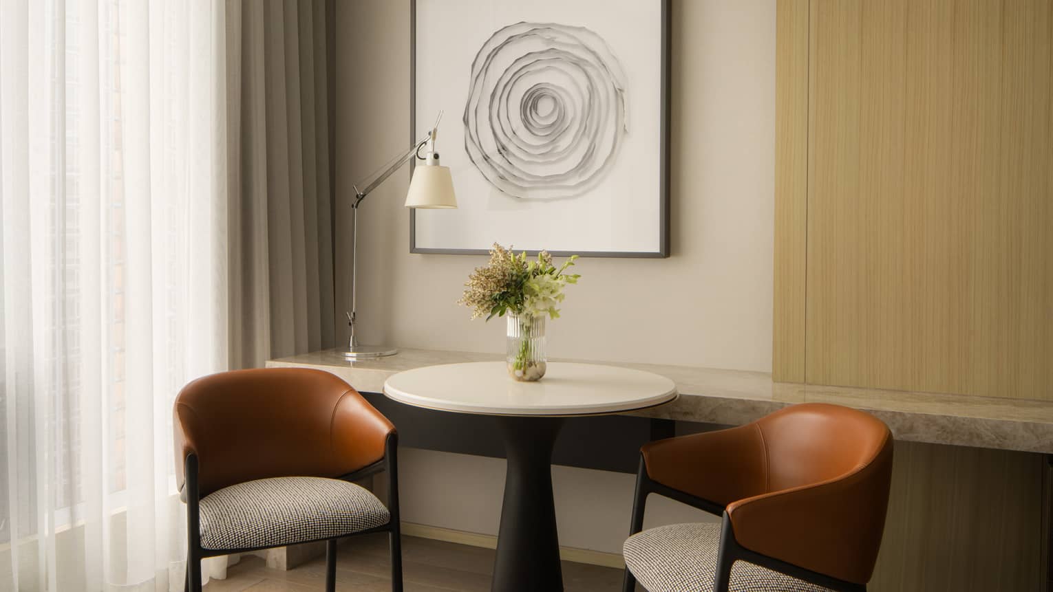 Hotel room with small round table and two chairs and hanging artwork at Four Seasons Hotel Toronto