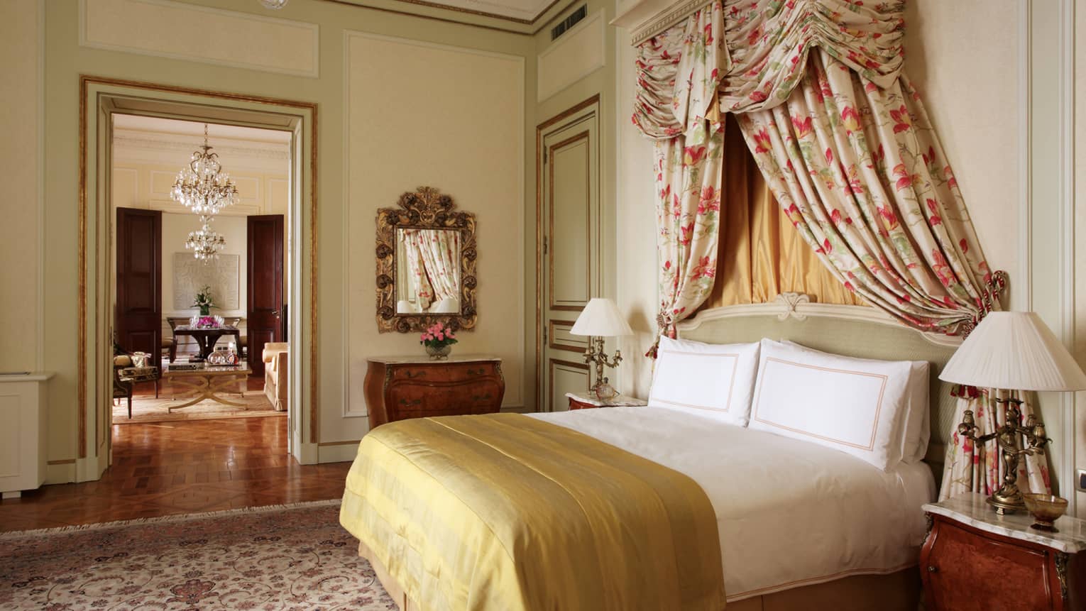 La Mansión Presidential Suite bed with gold blanket, floral drapes above headboard, door to dining room