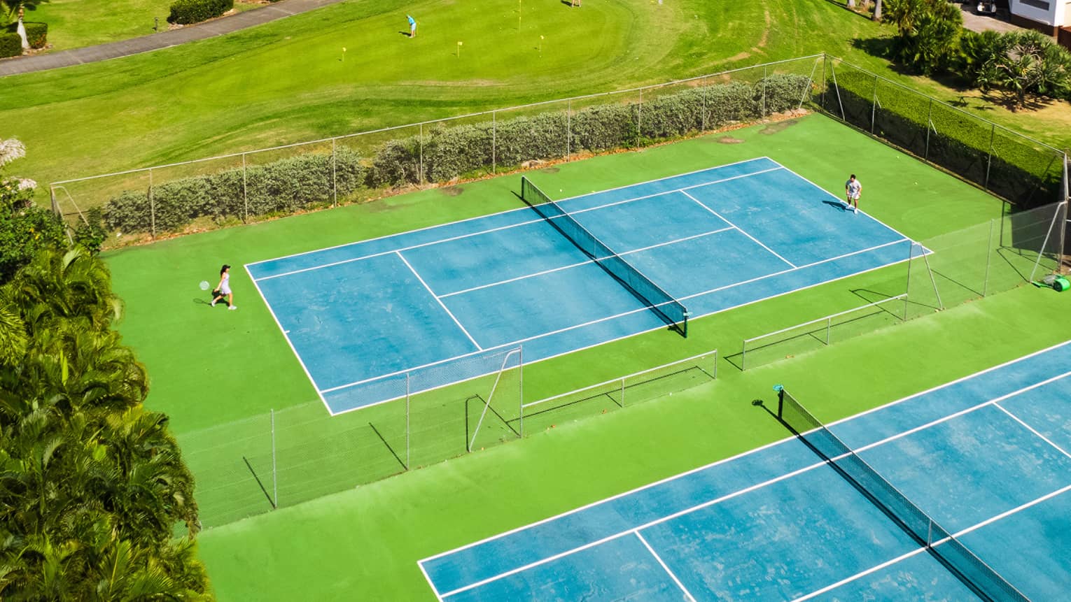 Two tennis or pickleball courts with a mountain in the background on a bright day.