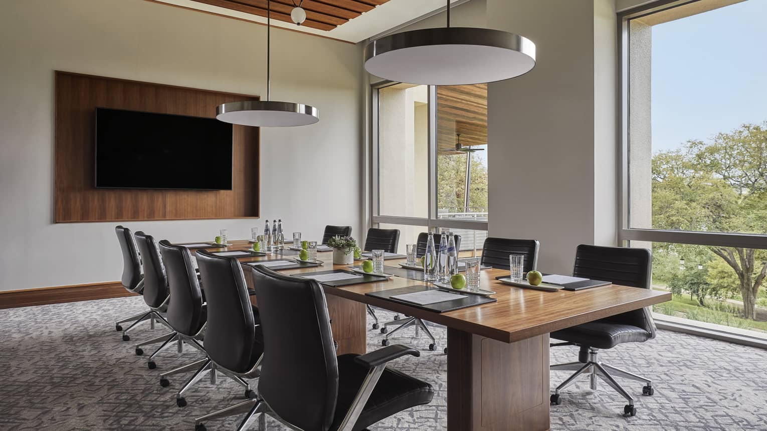 Leather swivel chairs around wood boardroom table in bright Waller Creek room
