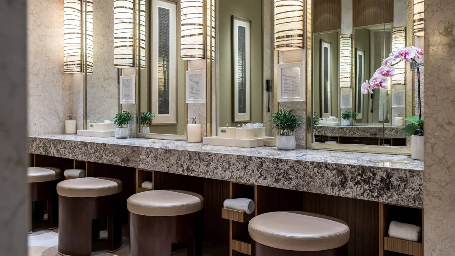 A modern spa vanity with rounded stools, rectangular mirrors and granite countertops