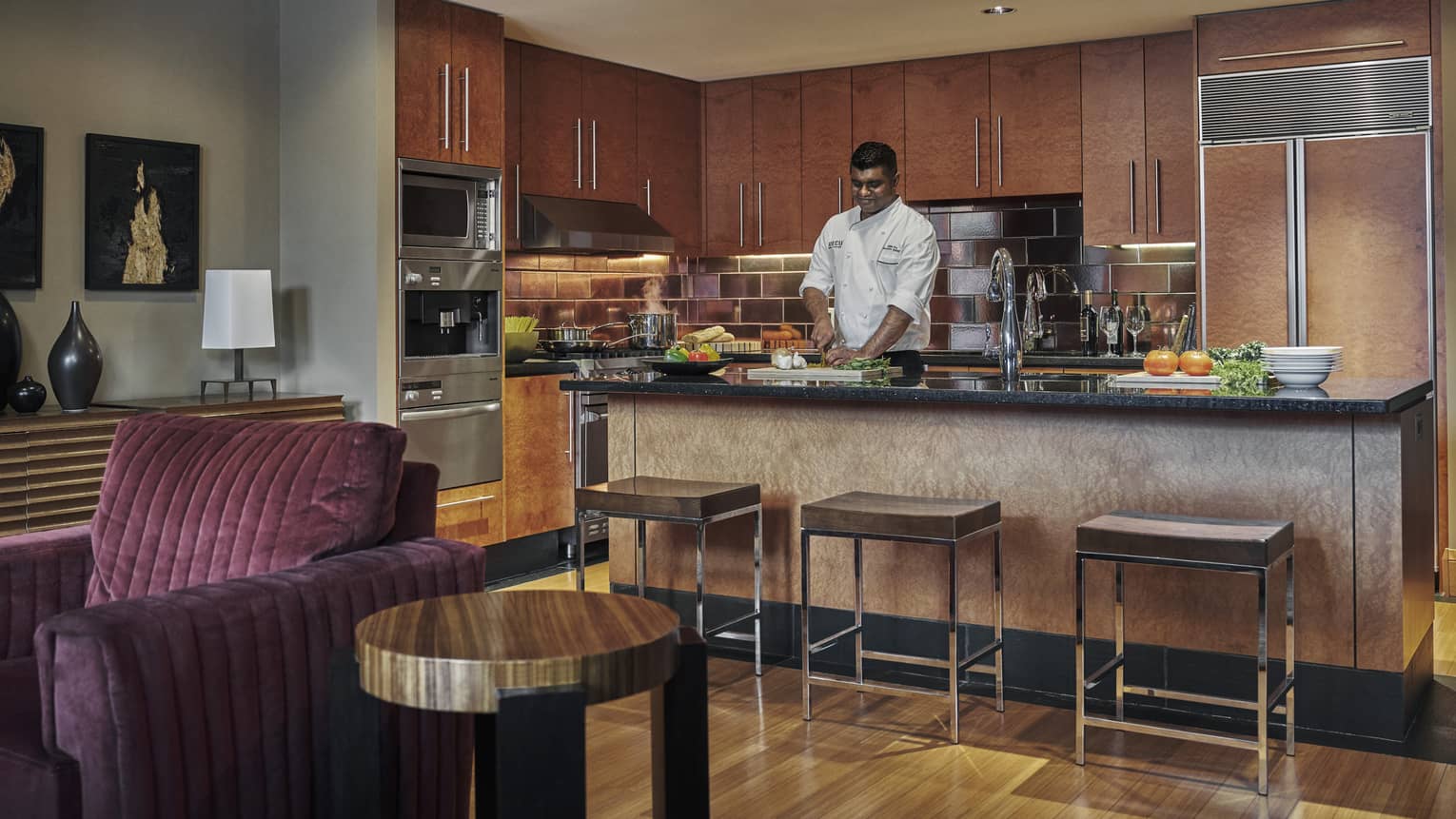Chef prepares meal in kitchen that overlooks living room
