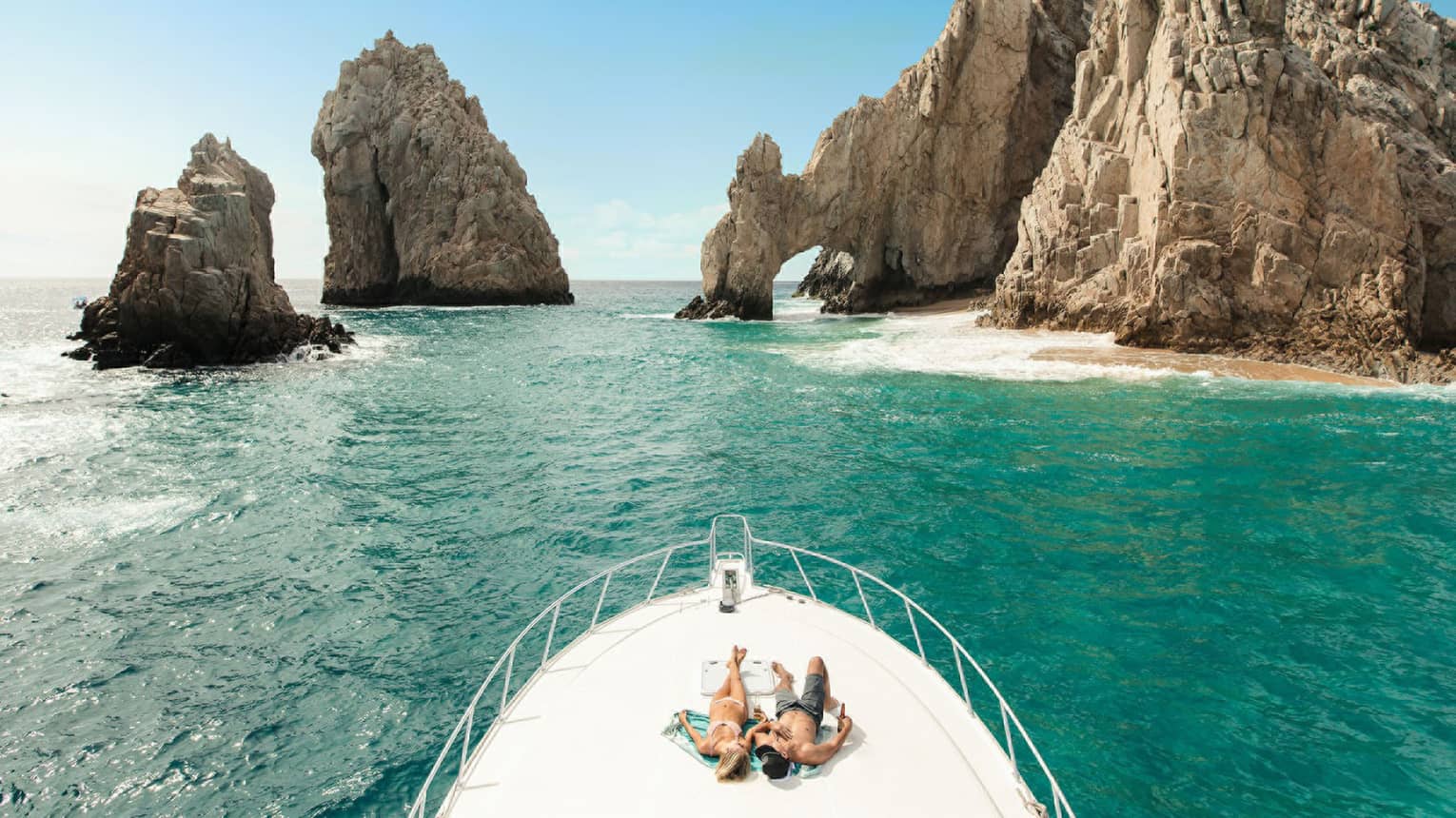 Two people lay on front of boat in Cabo