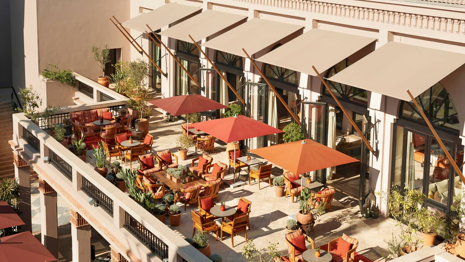 Aerial view of sunny patio with dining tables, chairs, orange umbrellas