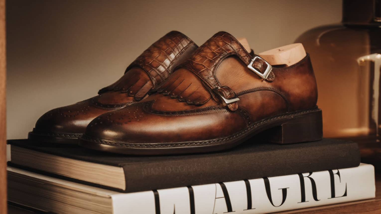 Brown leather shoes with silver buckles placed on top of two books.
