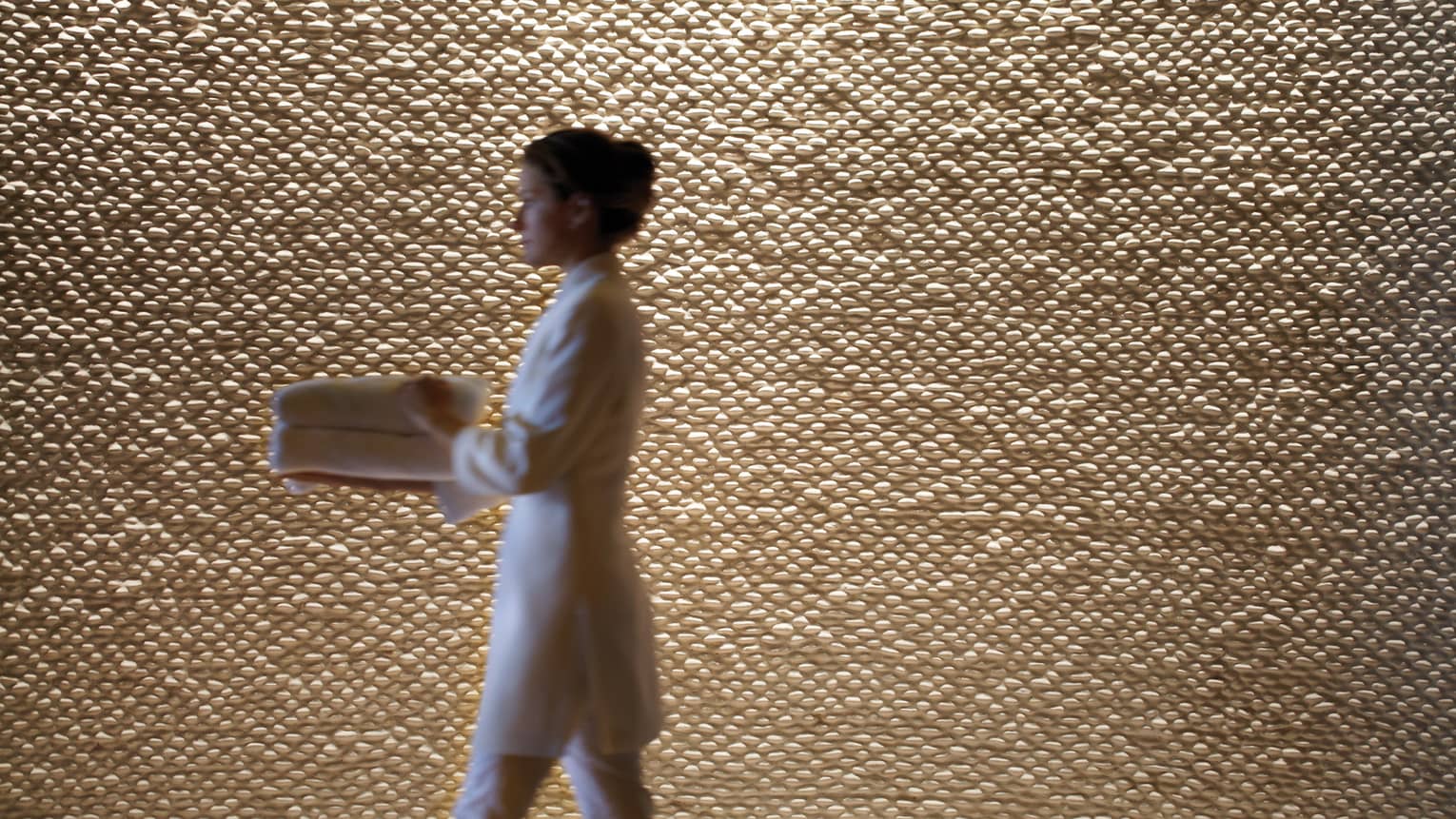 A woman in a spa robe walking by a wall.