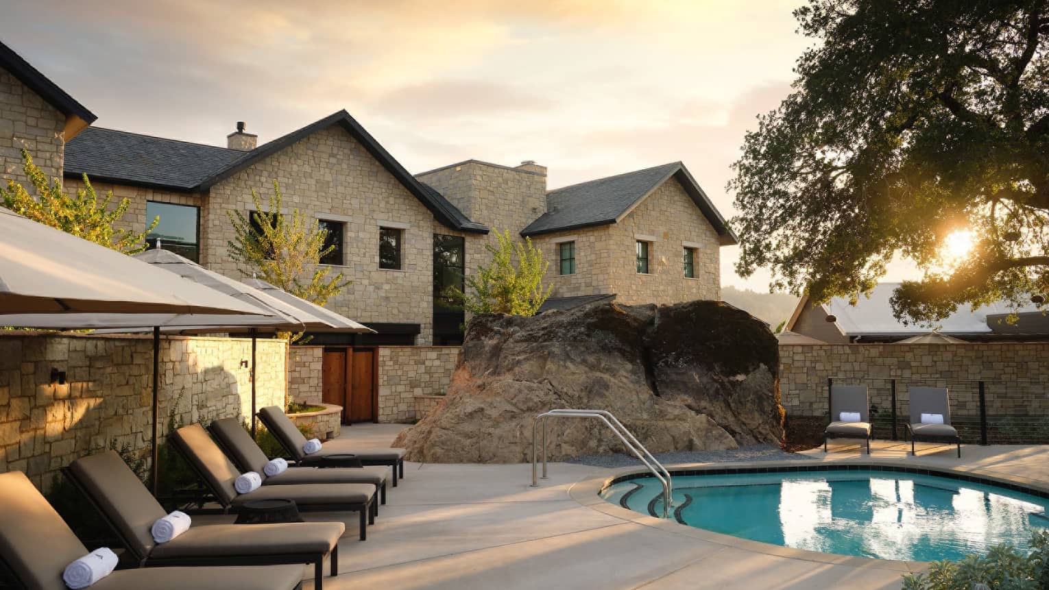 Pool and cushioned lounge chairs with umbrellas