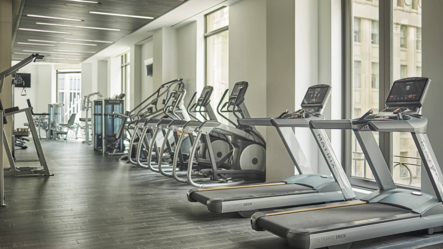Treadmills, cardio machines in row by windows in Fitness Centre