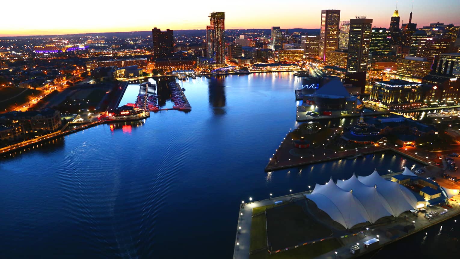 View of the harbour in Baltimore at dusk, surrounded by city lights
