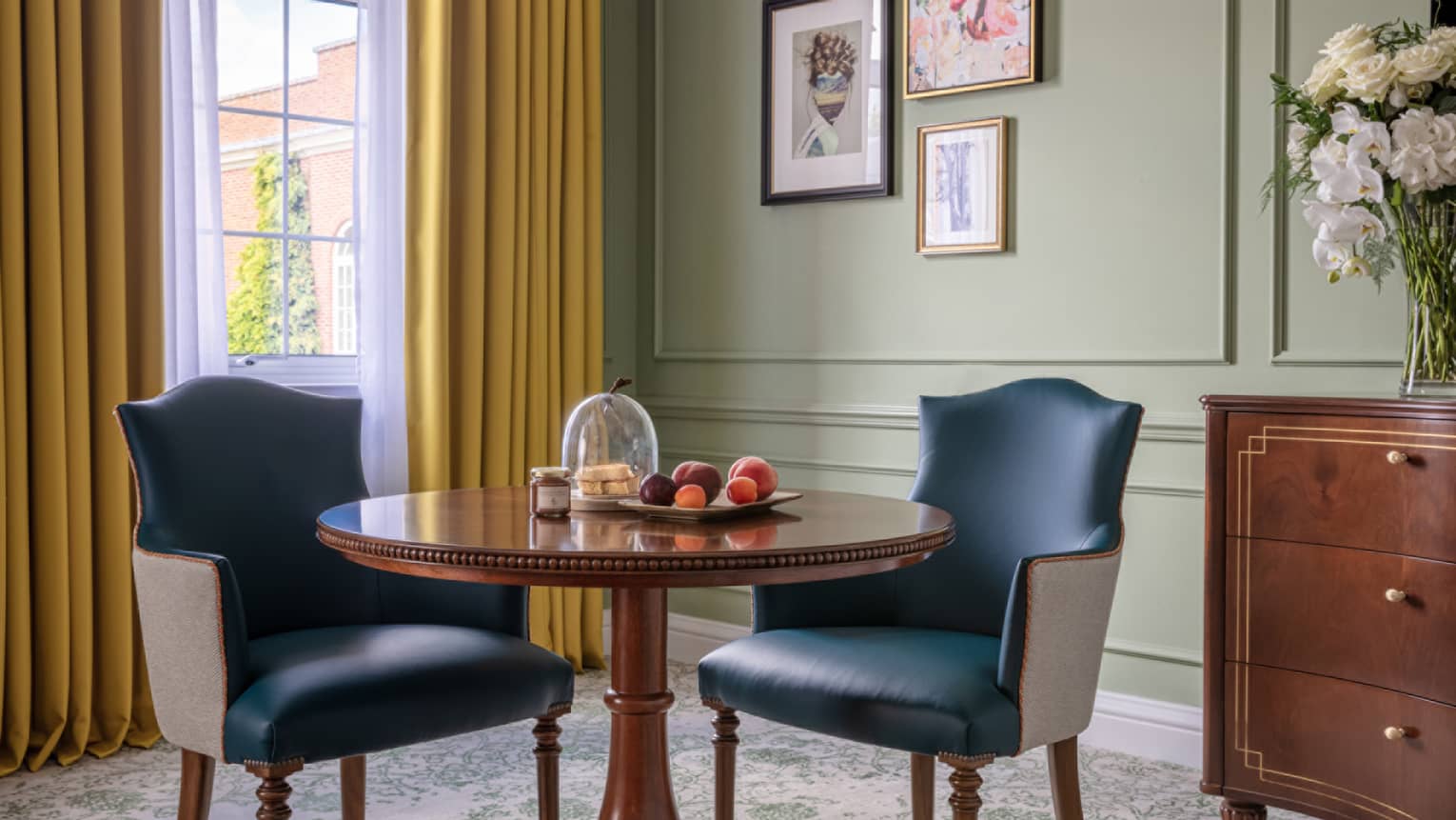 Table for two with blue leather chairs, cherry wardrobe, floor-to-ceiling window with yellow drapes