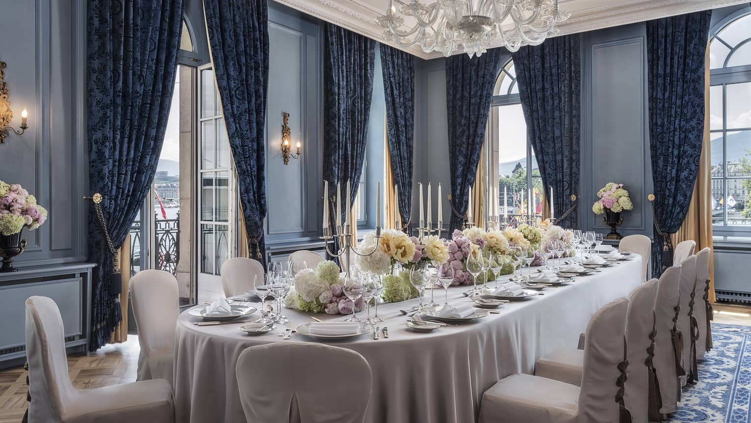 Salon Petit Mont Blanc large dining table with white linens, flowers, corner windows 