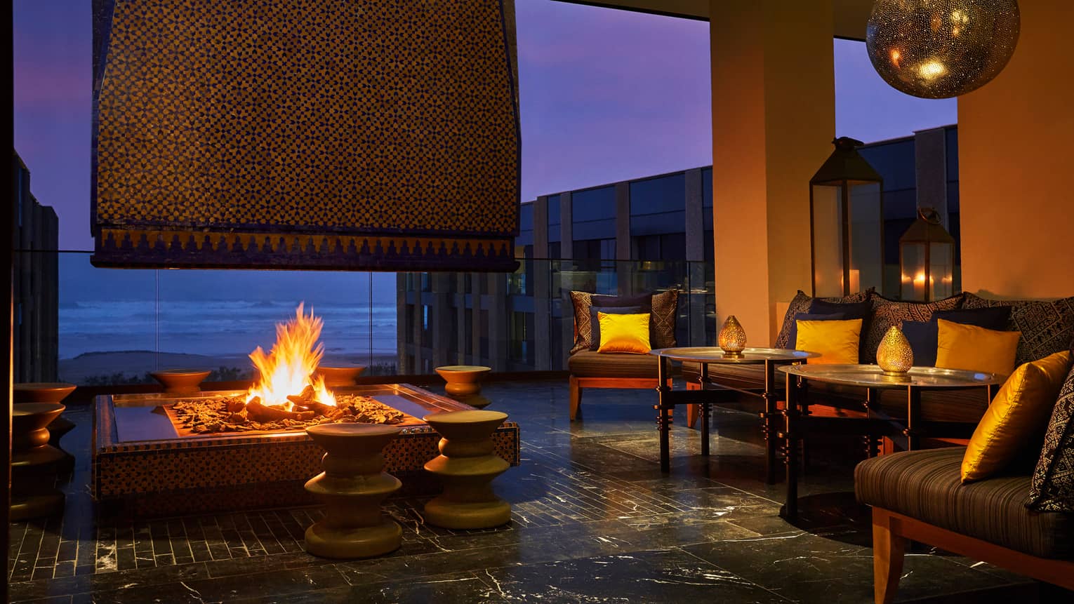 Patios sofas, beaches around large outdoor fireplace on Mint terrace at night