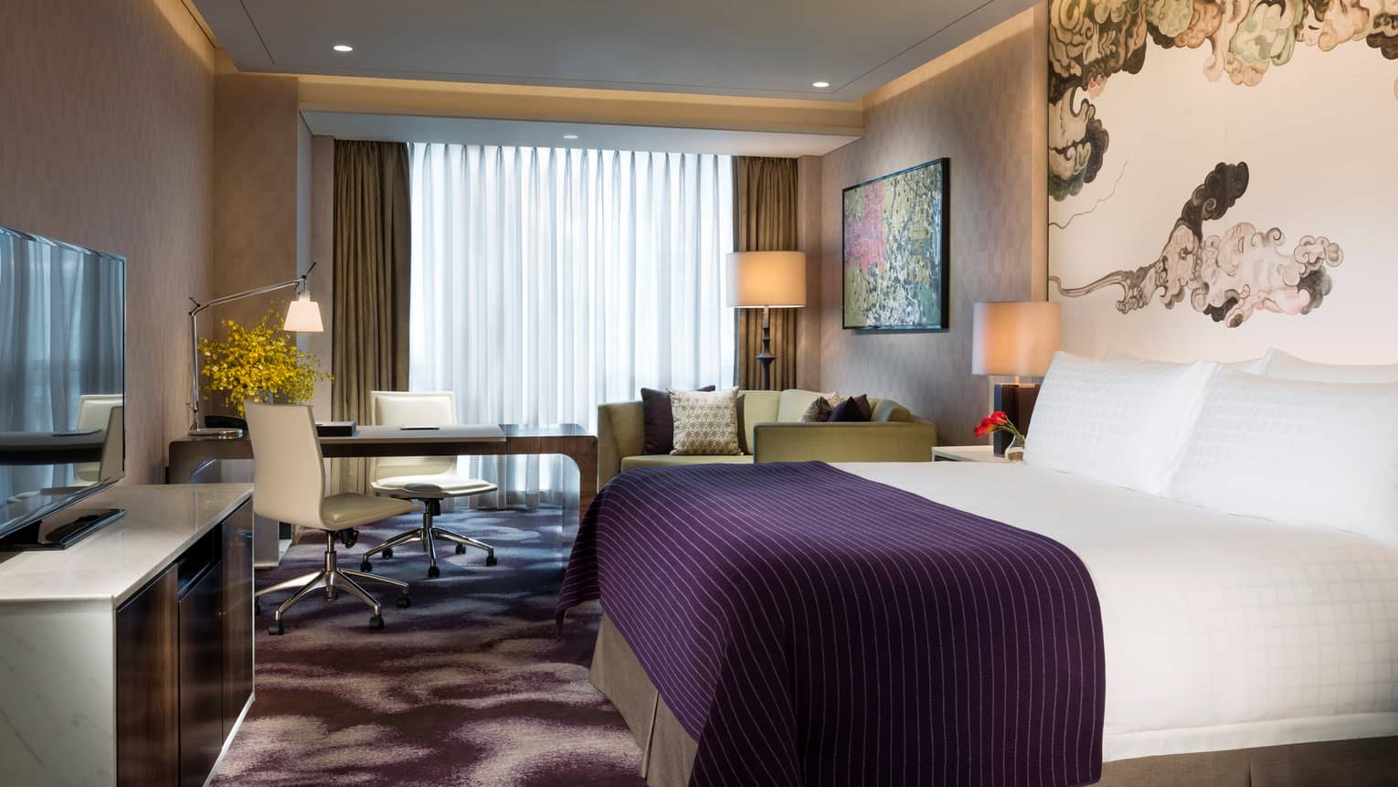 Premier Room hotel bed with indigo blanket, dresser and TV, desk by window