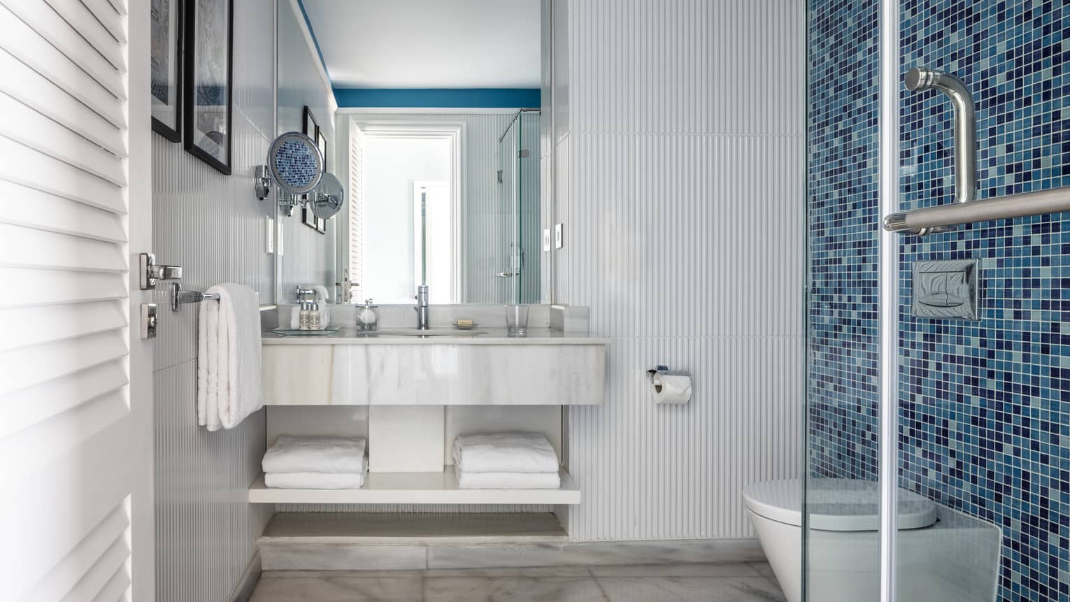 Suite bathroom with walk in shower, blue tiled wall, double vanity, mirror
