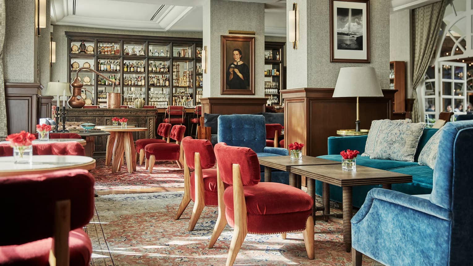 Fifty Mils dining room with red and blue velvet chairs, tables, antique-style bar, framed oil portrait