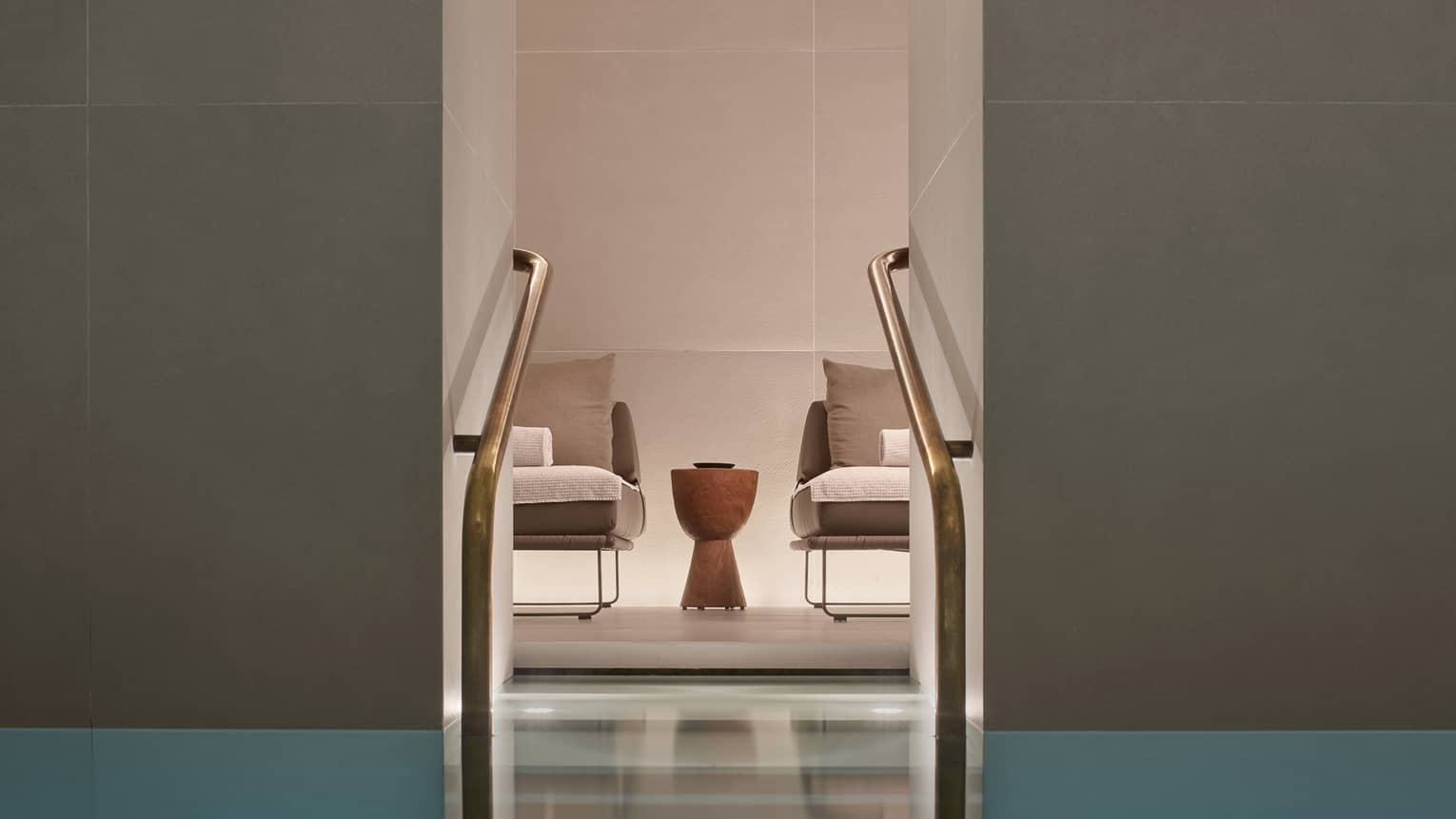 Two chairs and small table as seen from Milan Spa lap pool staircase with railings