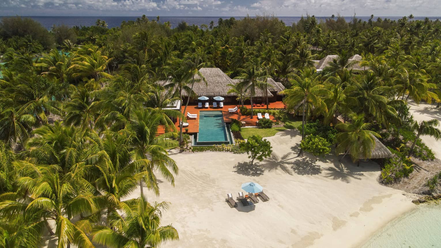 Aerial view of Bora Bora villa with pool on edge of beach, surrounded by palm trees