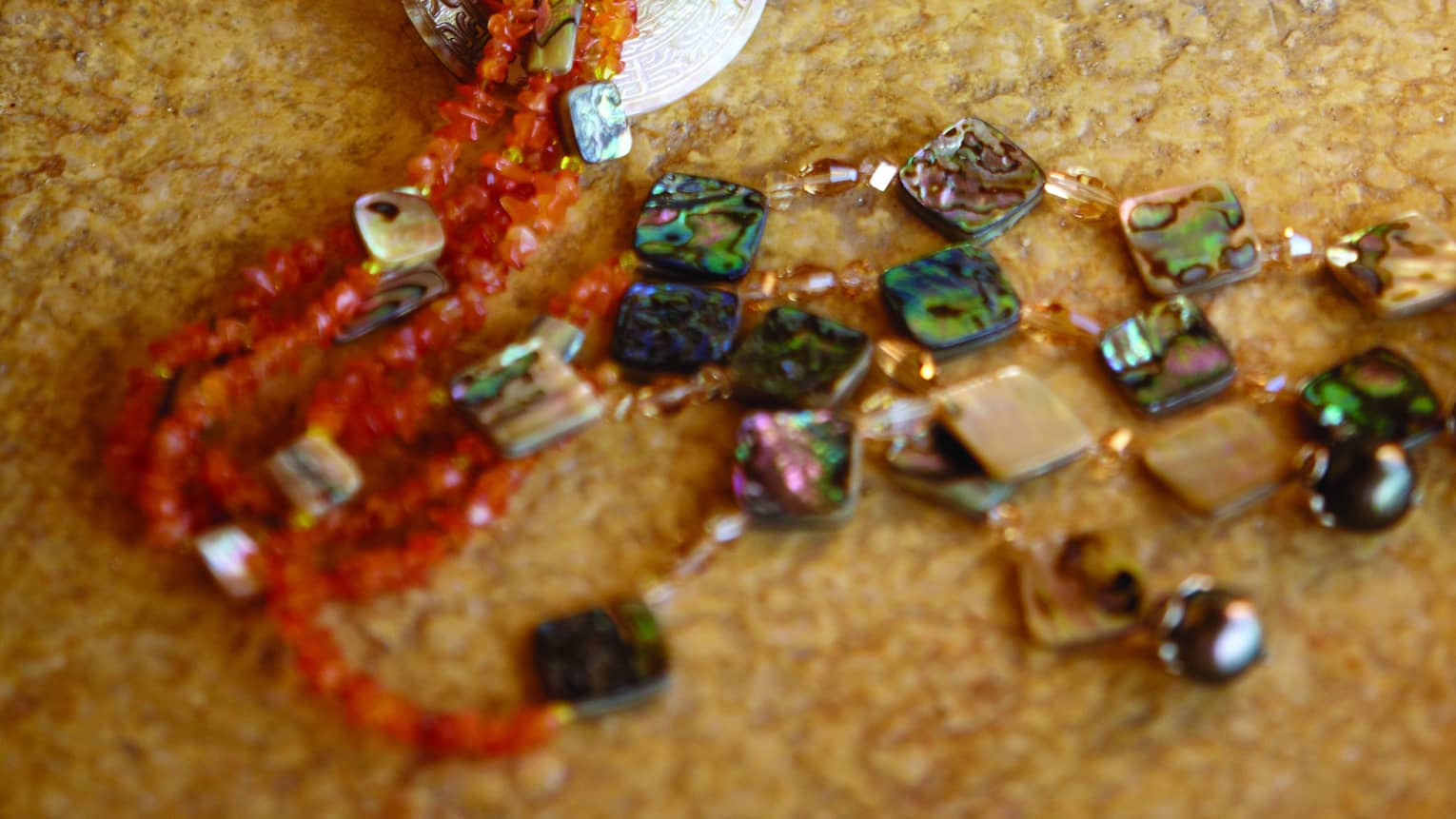 Stone and gem jewelry on a beige surface.