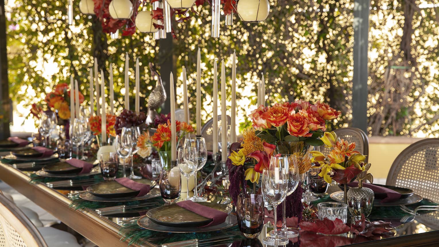 Garden wedding dining table set with long candles, orange red and yellow flowers