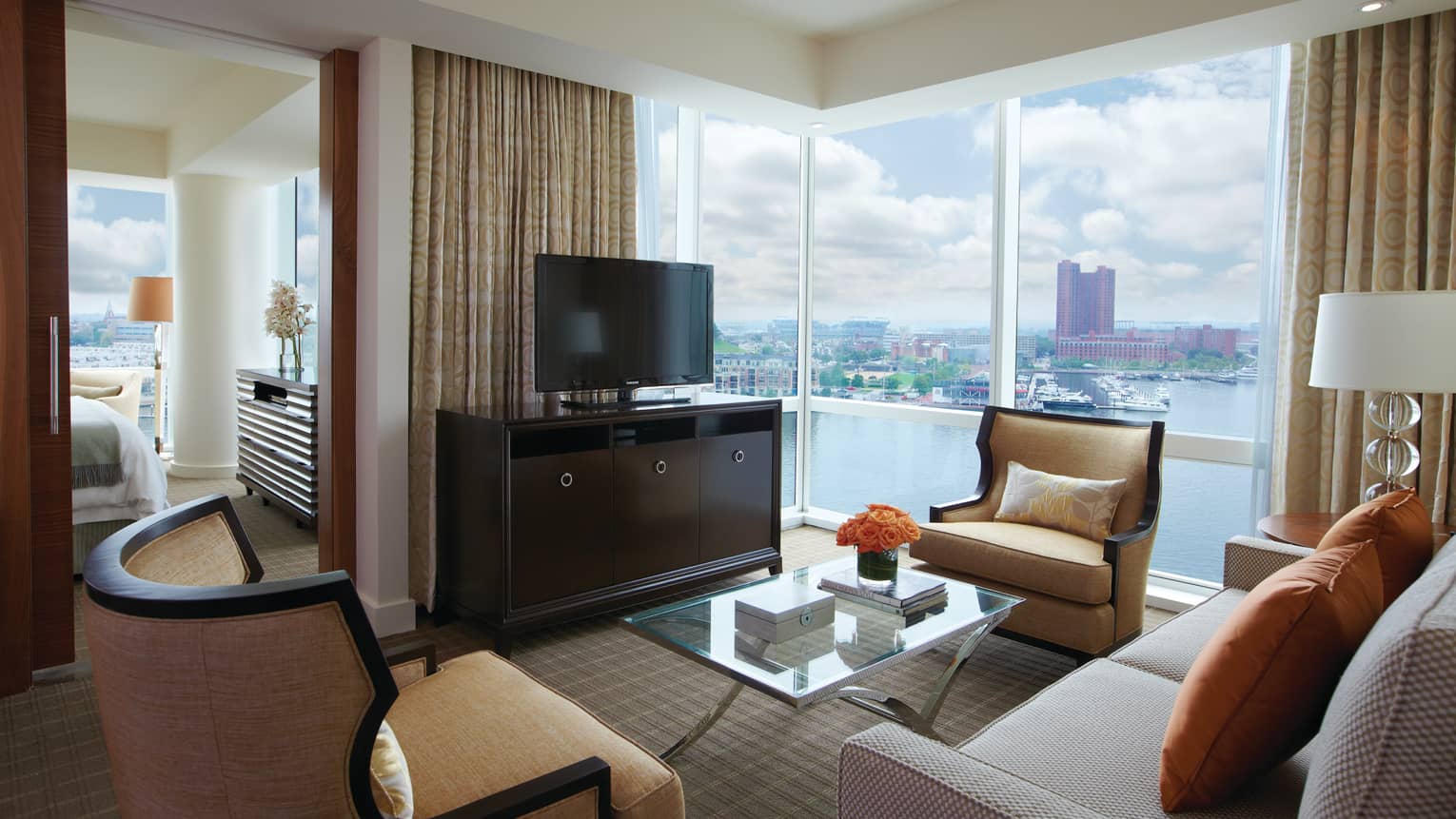 Executive Suite living room sofas, armchairs, TV by bedroom door, window with harbour view