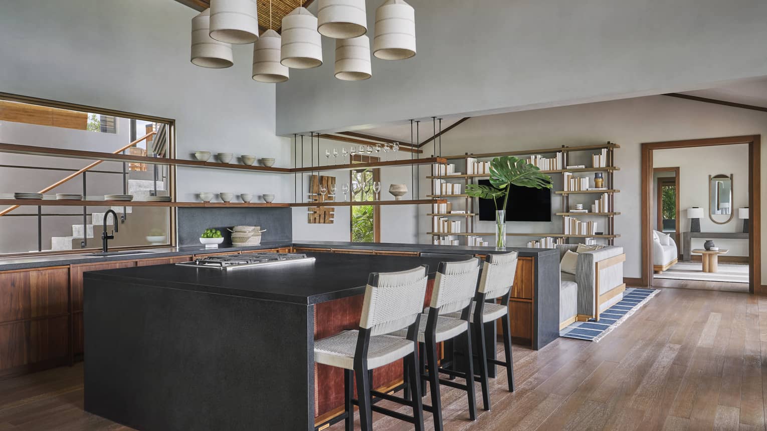 Kitchen with wooden floors, three counter-height chairs at island, multi-light hanging fixture