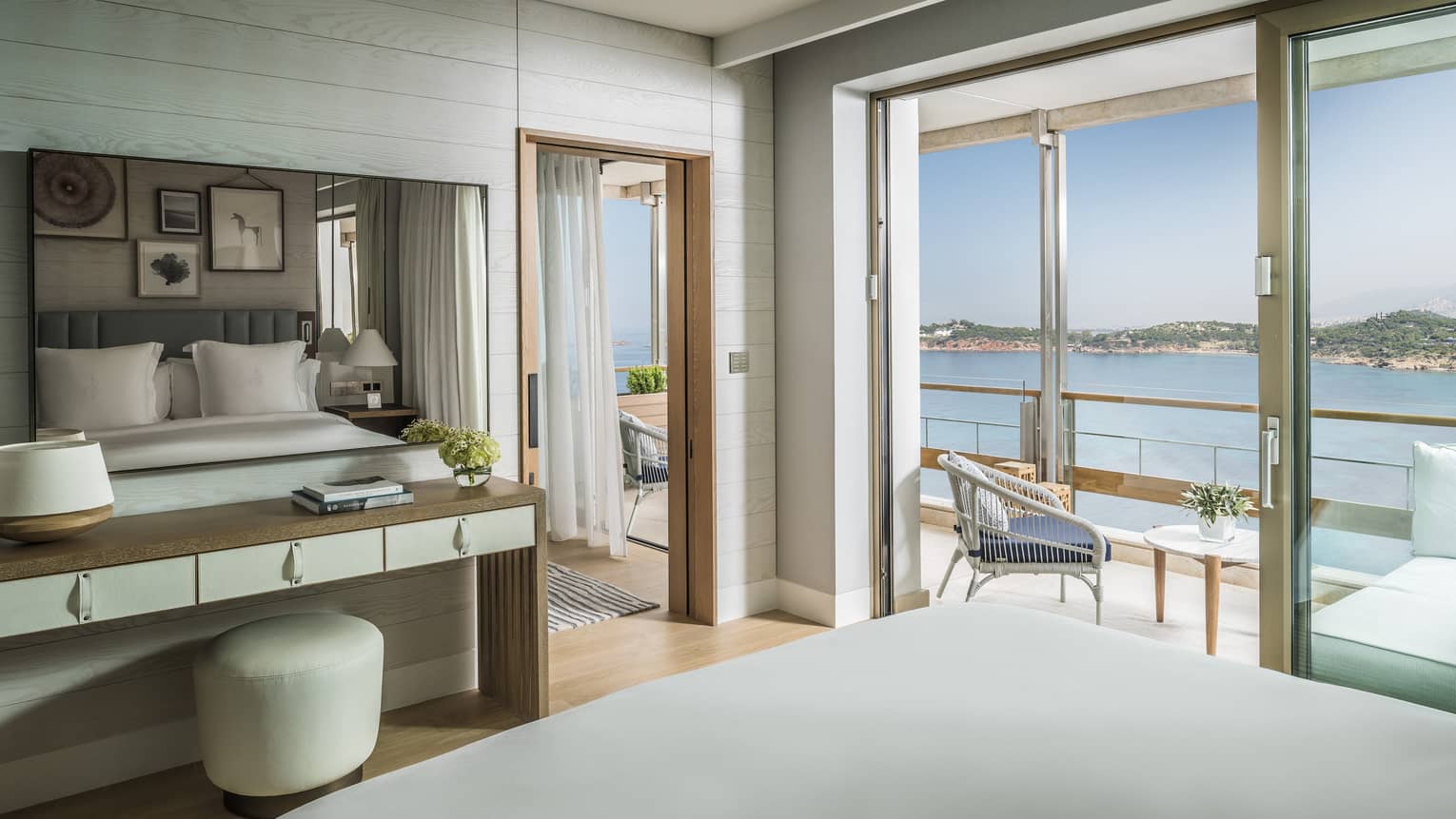 Arion Corner Suite hotel bed, tables, open balcony door with water views