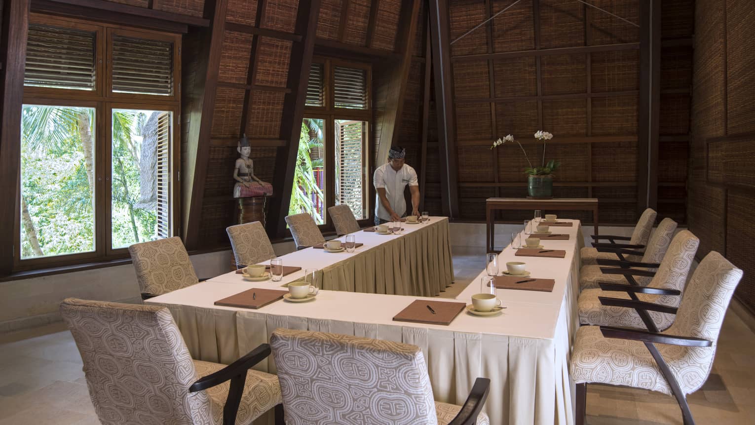 Hotel staff sets modular meeting table in Tirta Sari pavilion room near large windows