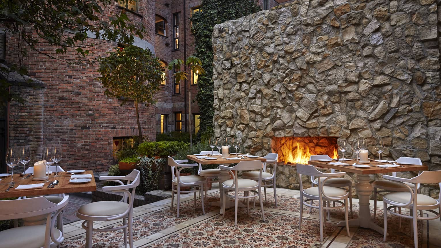 An outdoor patio with a fireplace, and several tables and chairs set up around.