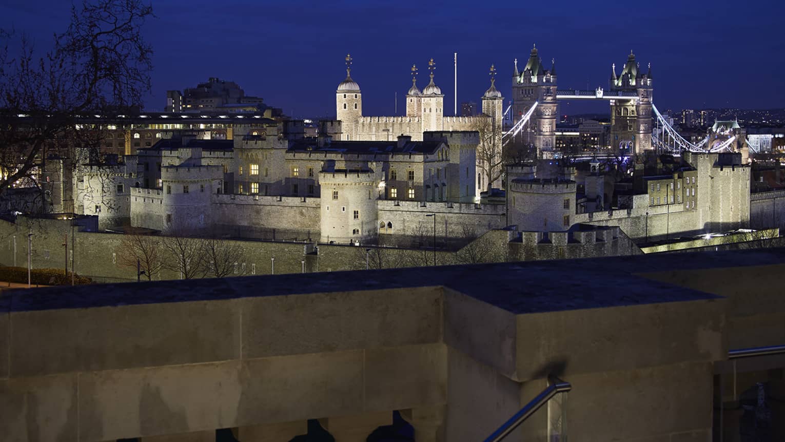 View over wall to Tower Bridge and the Tower of London at night