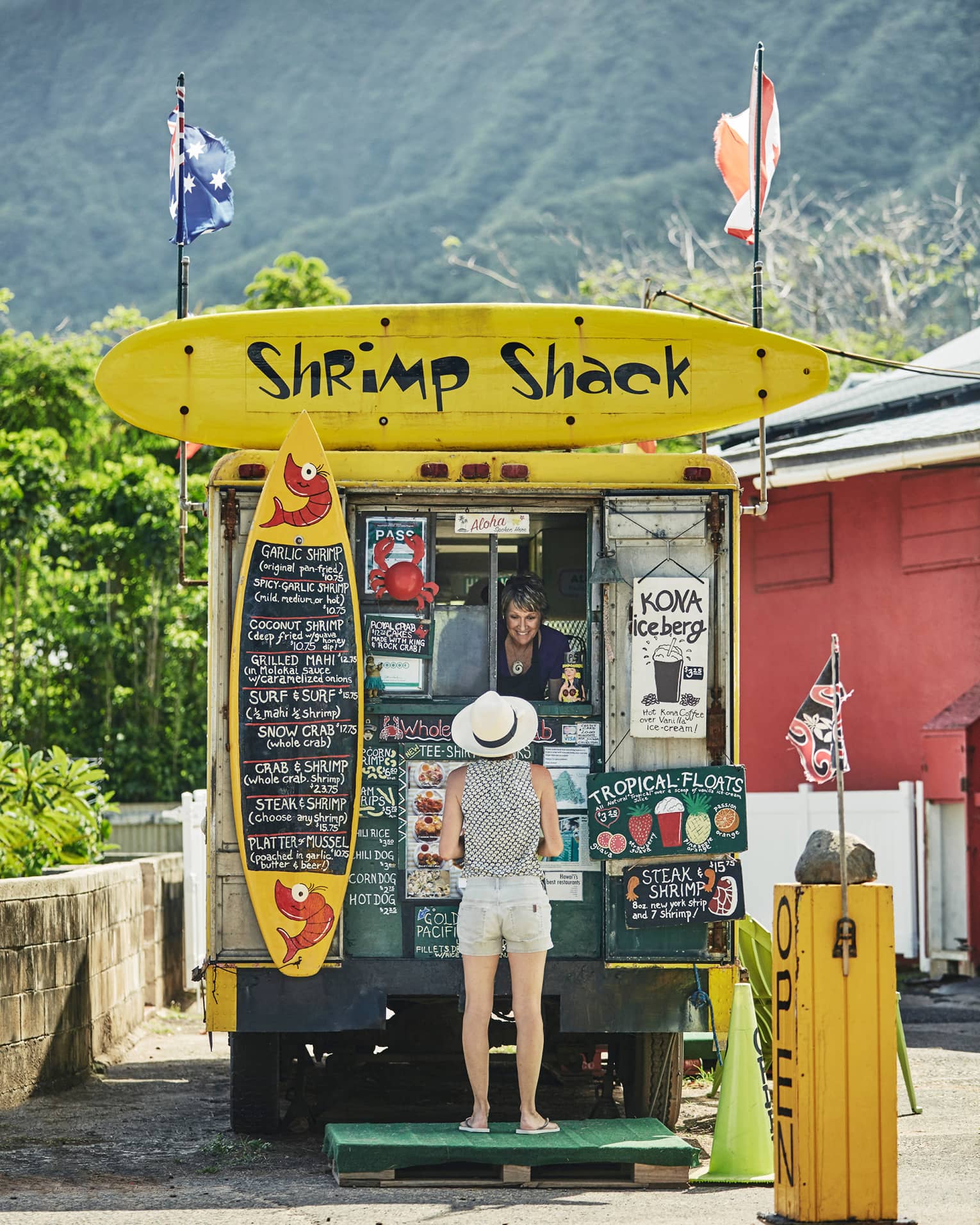Woman orders from Shrimp Shack food stand with colourful yellow signs 