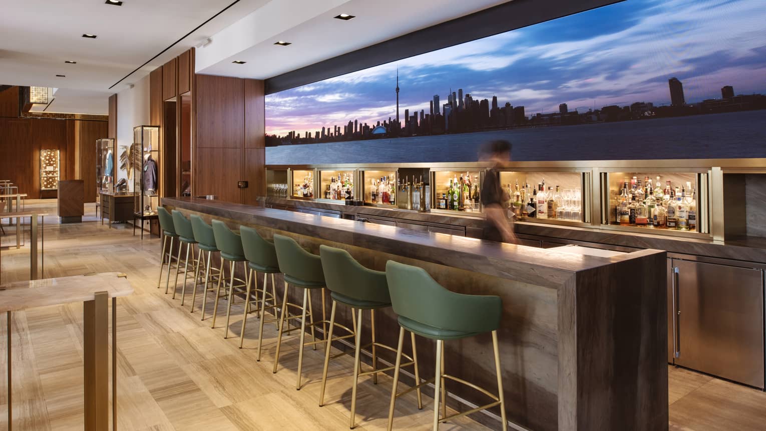 Upholstered chairs lined at a bar with a large image of the skyline 