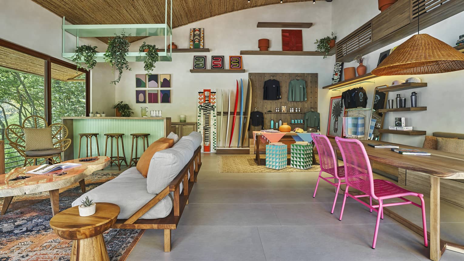 Indoor surf patio with futon and coffee table, service desk, wooden table with pink chairs