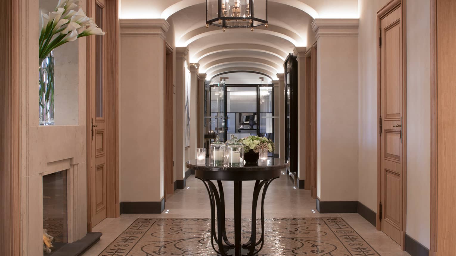 Hotel hallway with marble floors, round table with multiple white candles in glass votives, fresh flowers