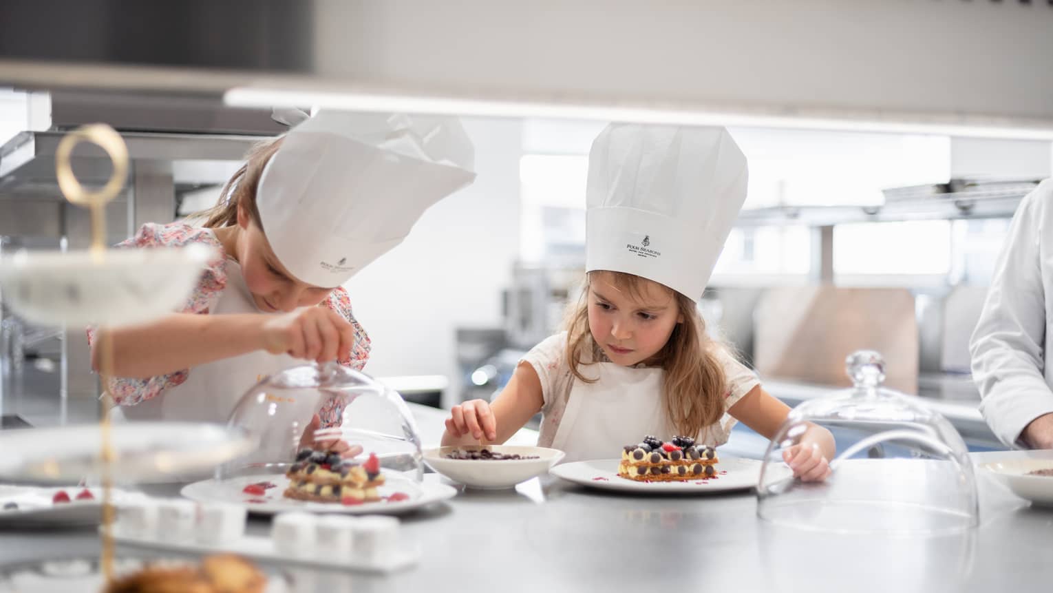 Two girls in chef hats making dessert in hotel kitchen