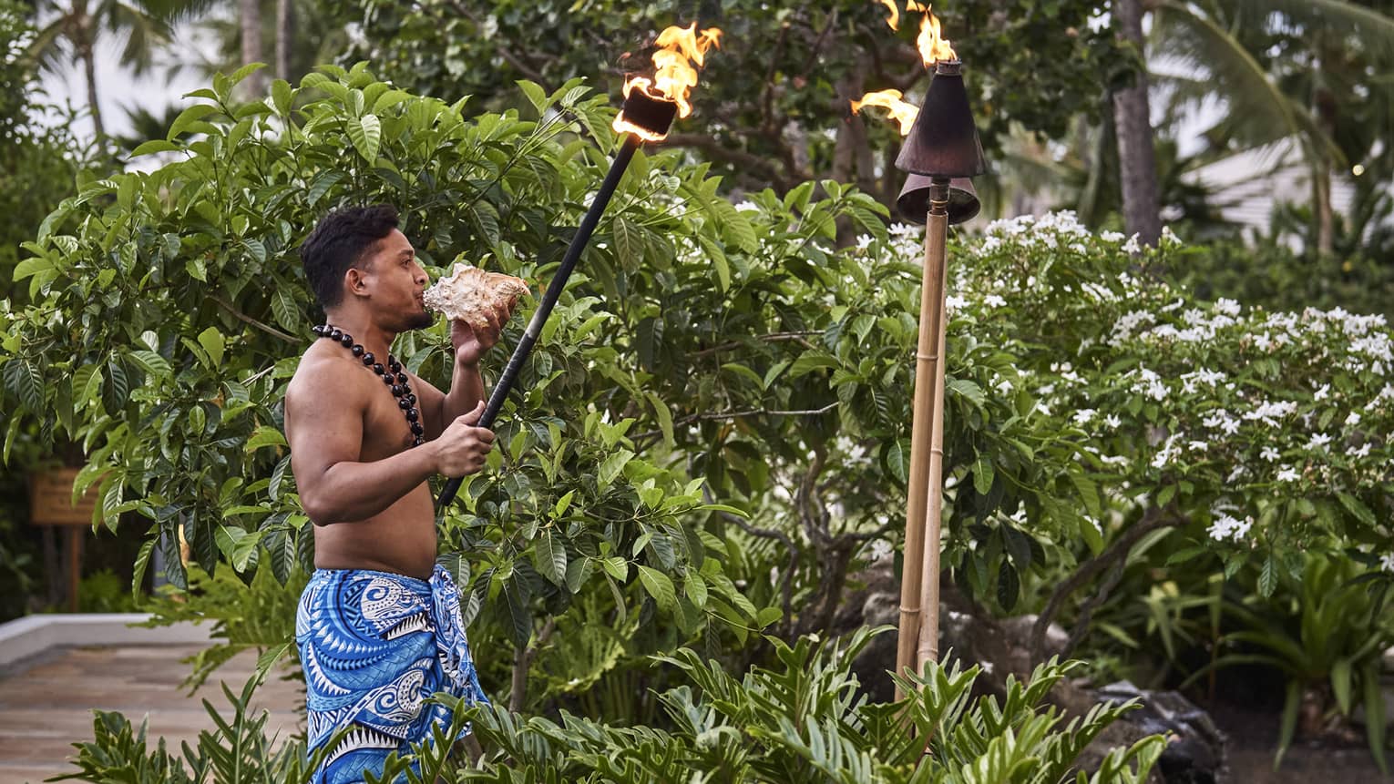Man lights a torch as he blows into a conch shell