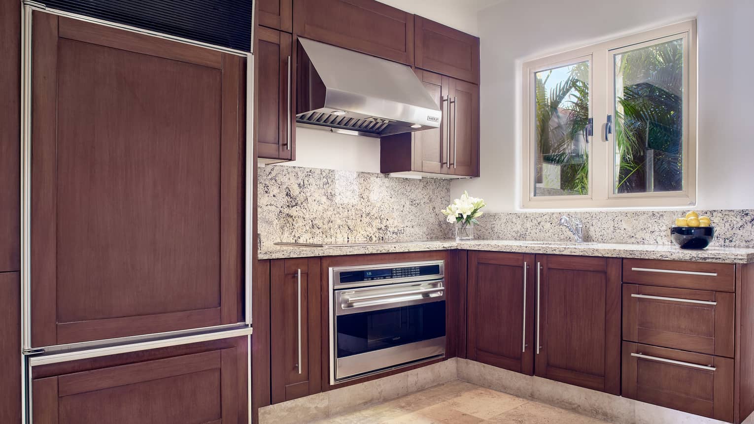 Arena Beach House kitchen with wood cabinetry, marble countertops, window