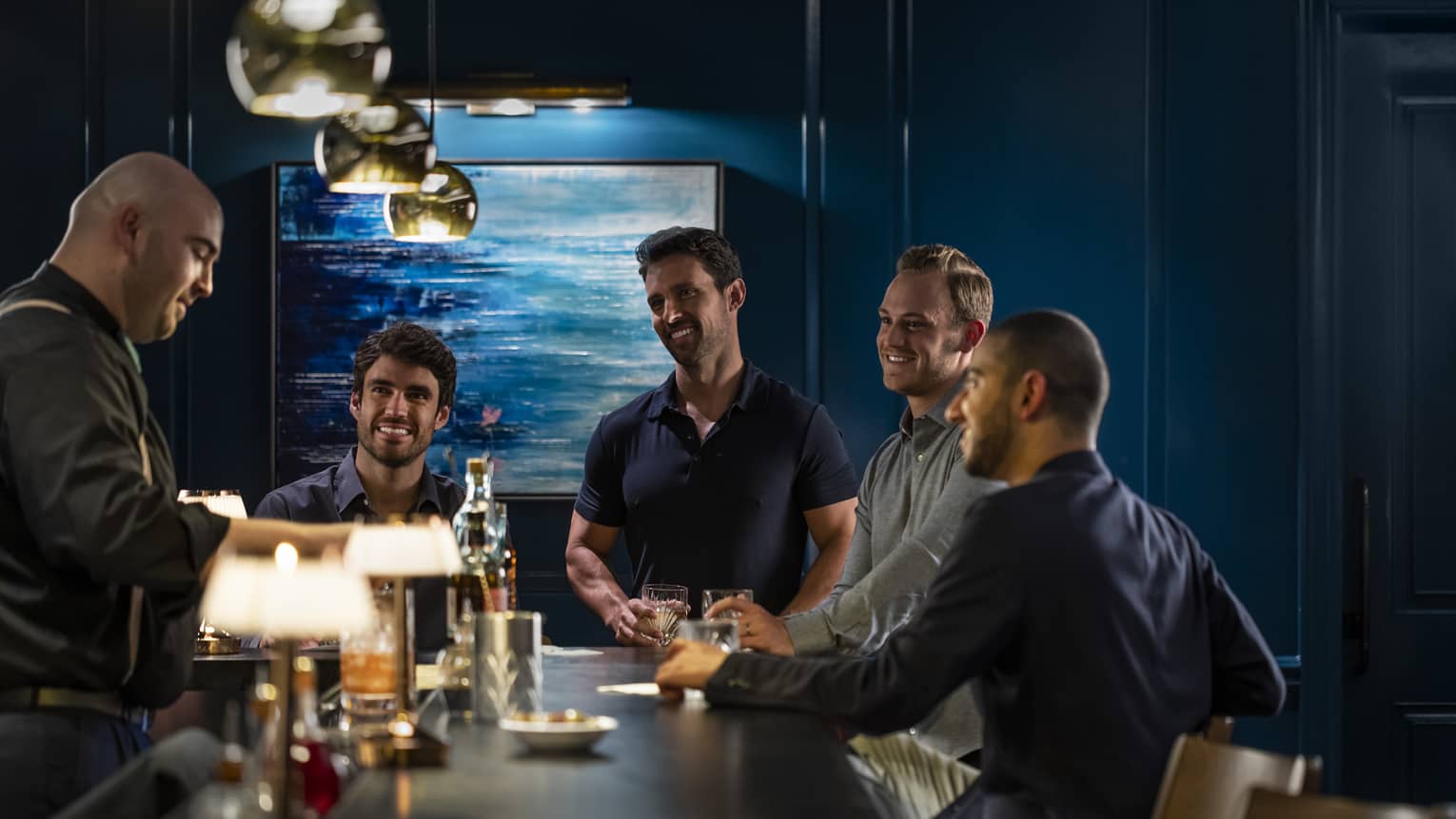 A group of men watch the bartender pour a drink 