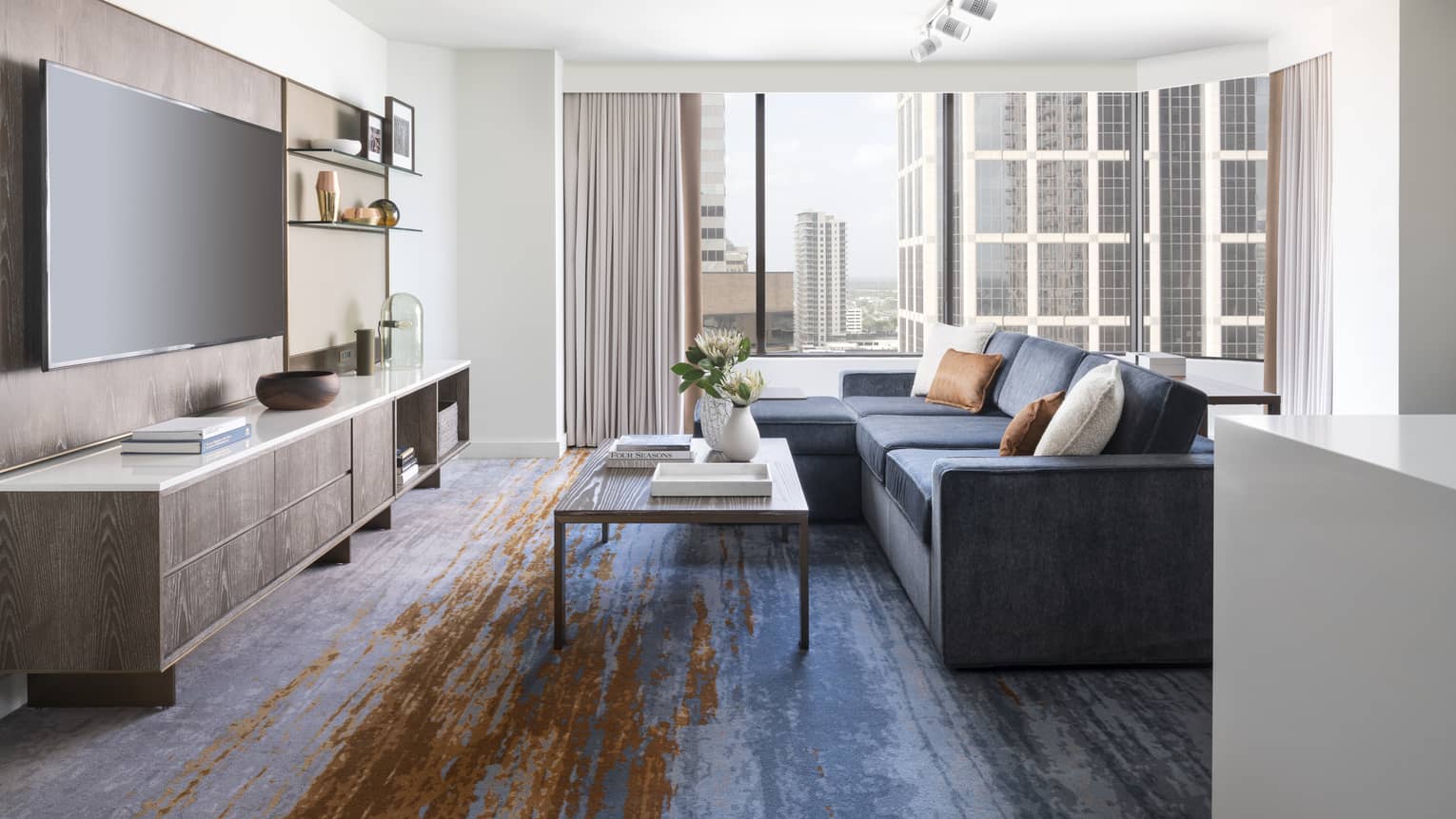 Two-bedroom Residential Suite living area with navy sectional sofa, floor-to-ceiling windows, city views