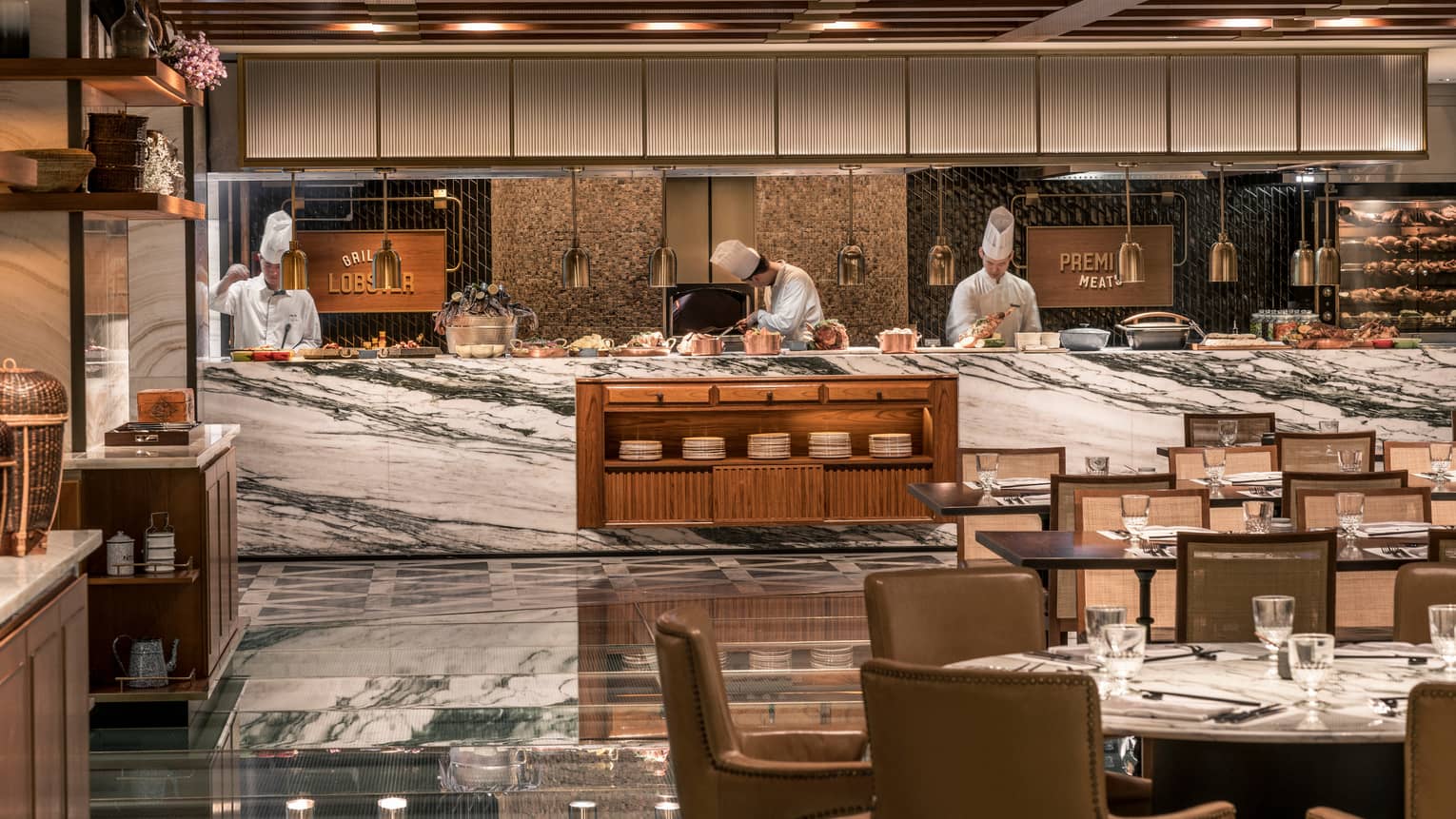 Chefs work behind white marble counter with copper pots at The Market Kitchen