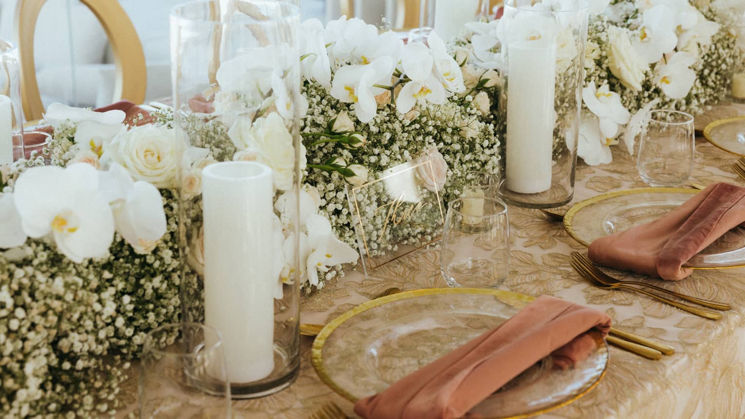 A large table with flower arrangements and candles along the center.