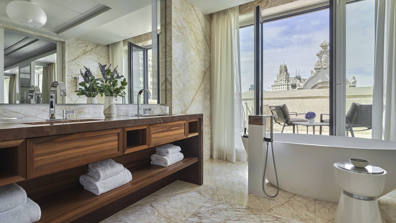 Guest bathroom with large soaking tub, double wooden vanity, mirror, marbled floors, floor-to-ceiling window