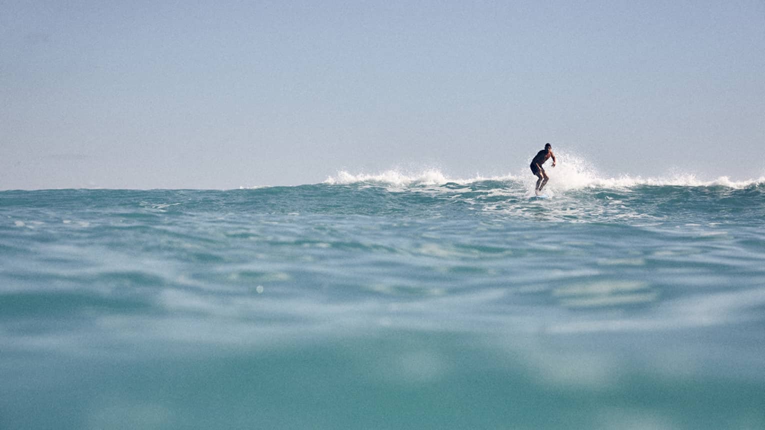 From the water's surface level, view of a man surfing
