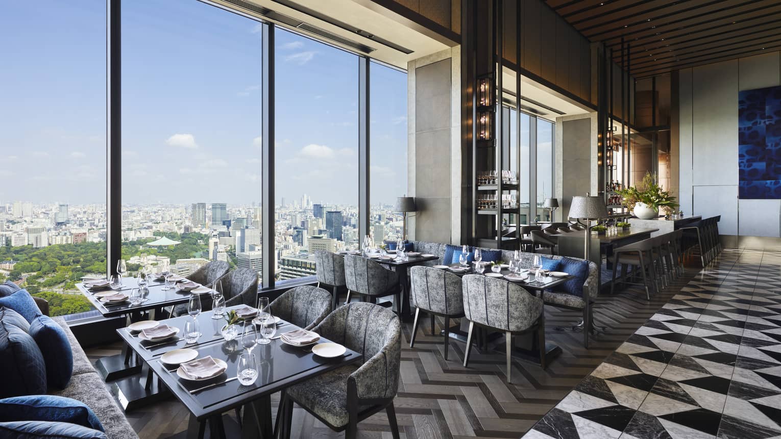 Four tables set for four with floor-to-ceiling windows, view of the city, natural light, grey and black colour scheme