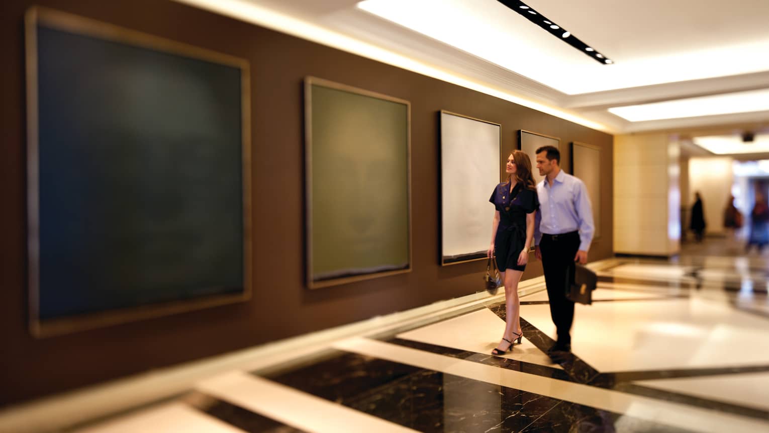 A man and woman walking through an art gallery.