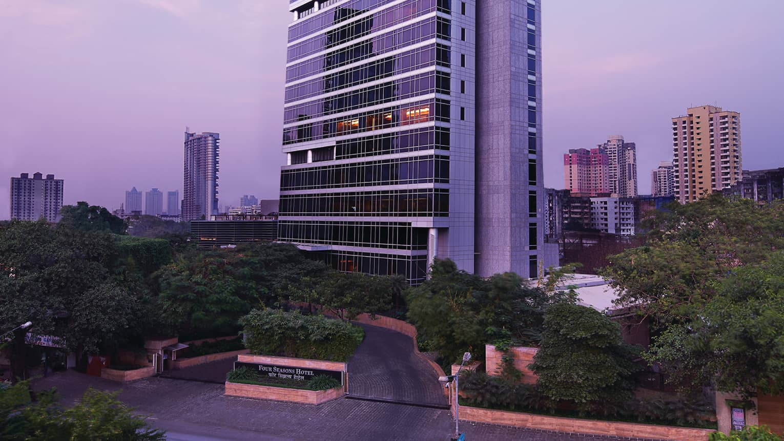 Four Seasons Hotel Mumbai glass tower exterior with trees around entrance, sign