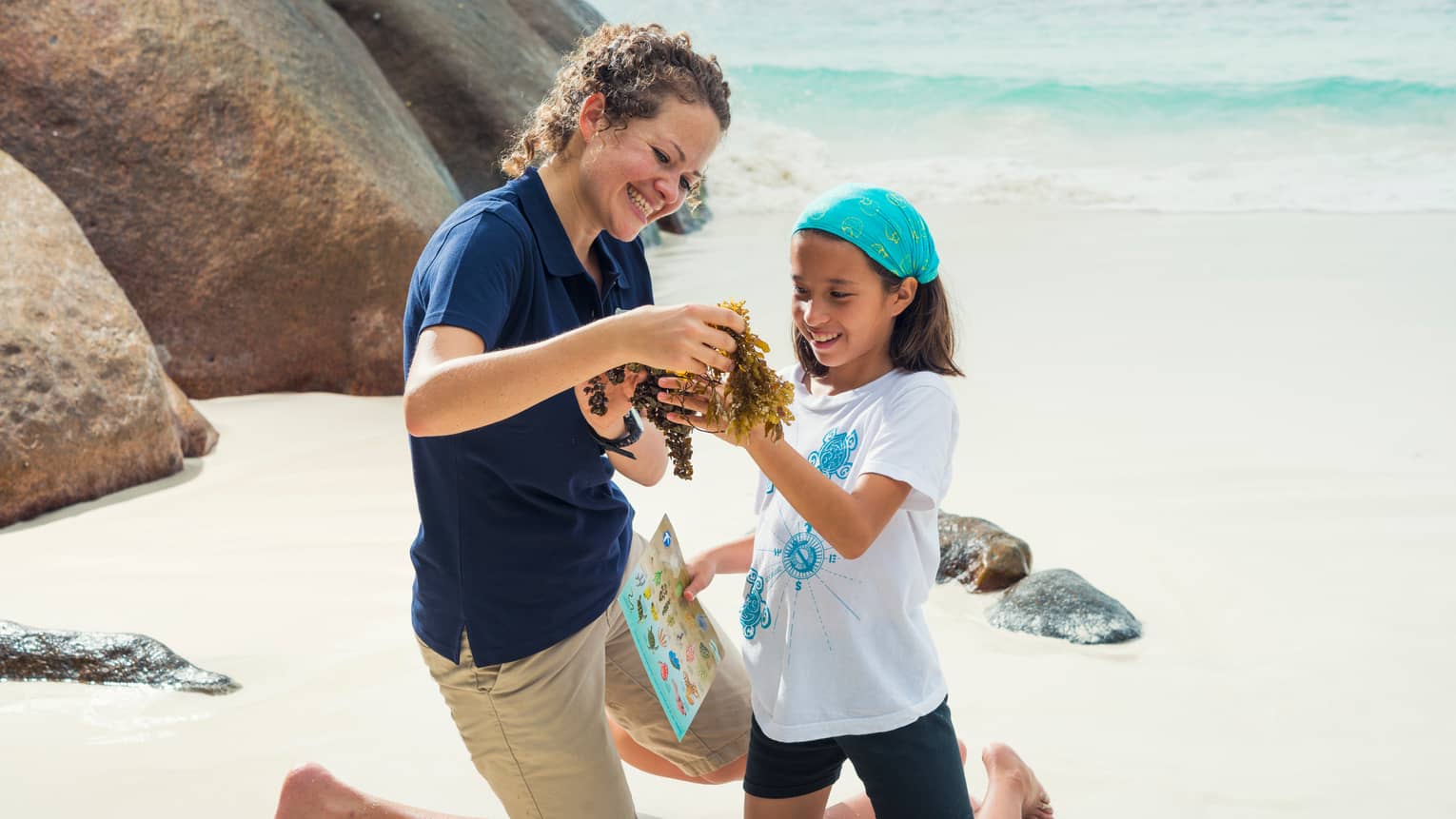 A WiseOceans female employee teaches a young girl about ecology on a beach