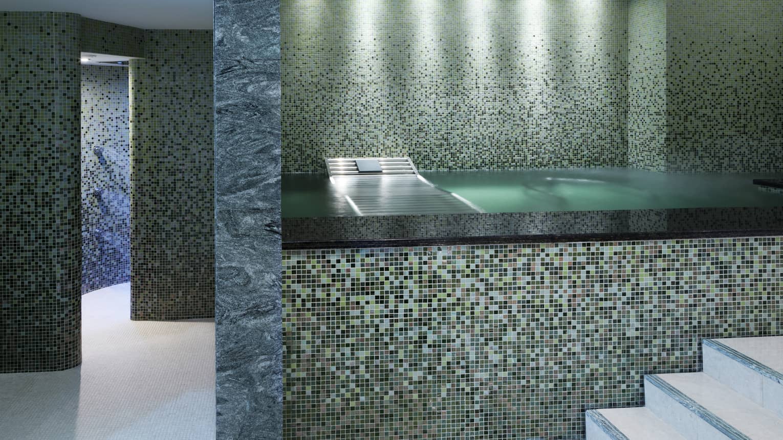 Raised bath with elaborate tile design in marble-and-tile spa room