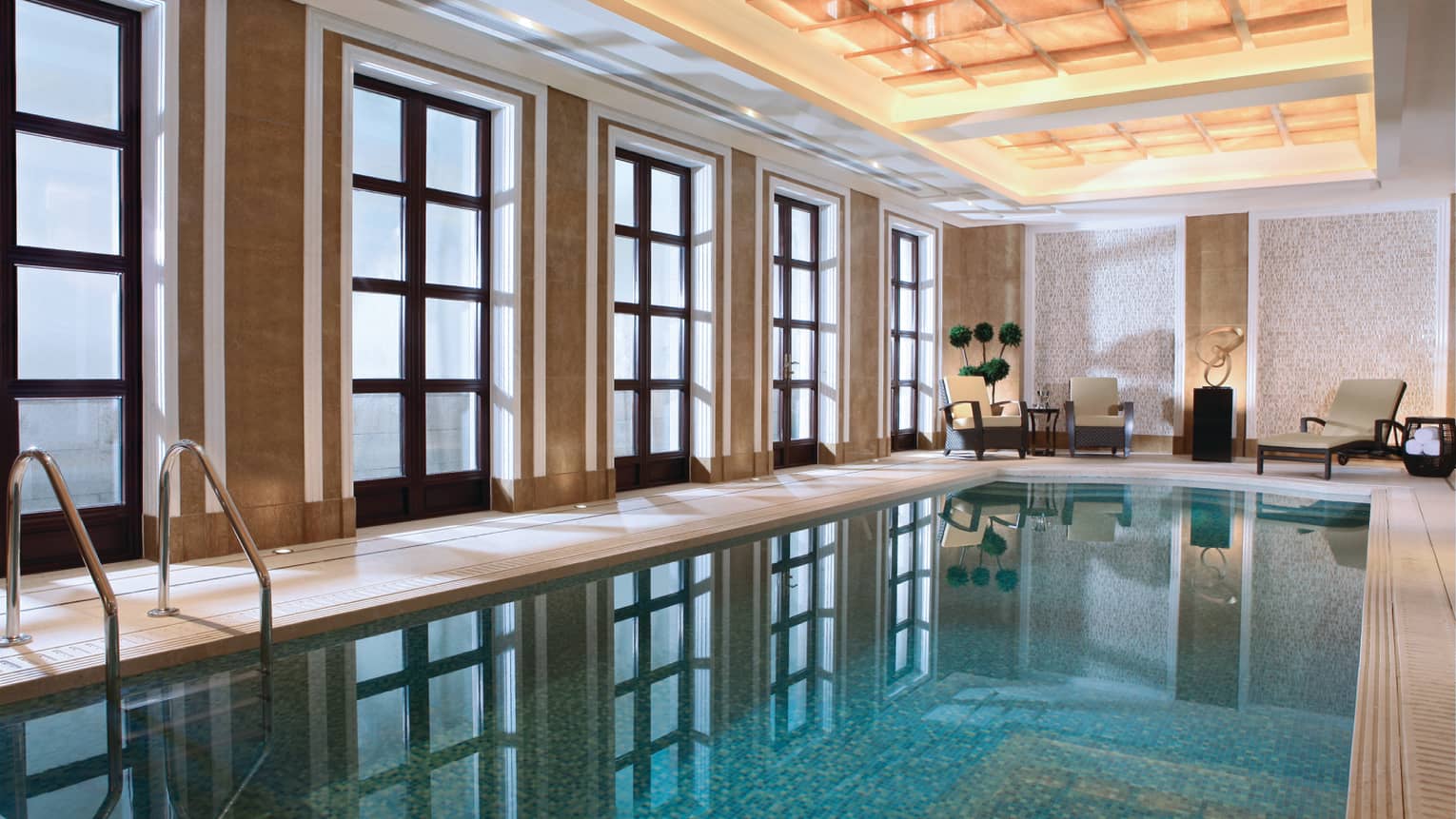 Floor-to-ceiling windows reflecting on long indoor swimming pool