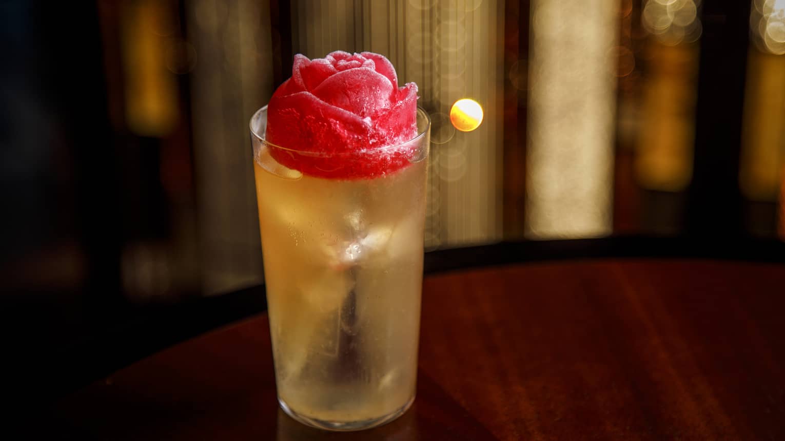 Yellow-hued cocktail in tall glass with rose-shaped ice cube